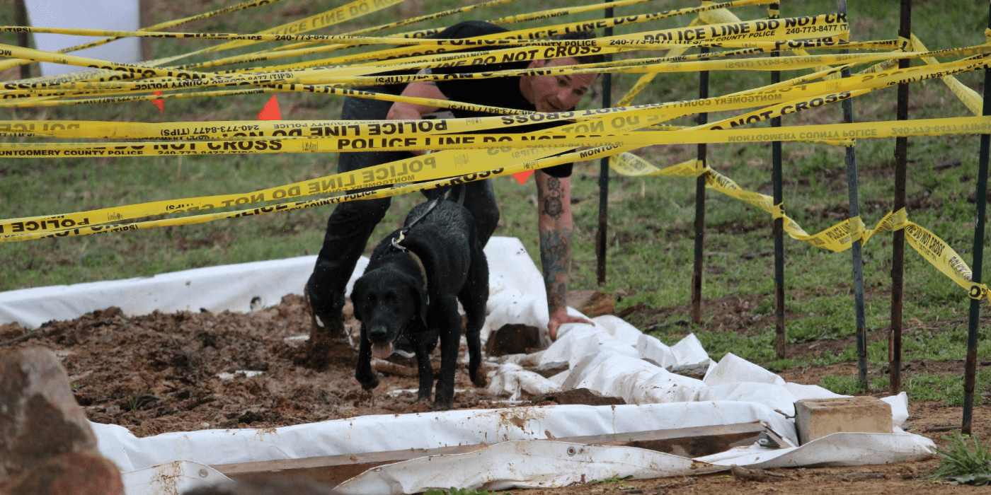 Photo of a person and a dog going through the mud.